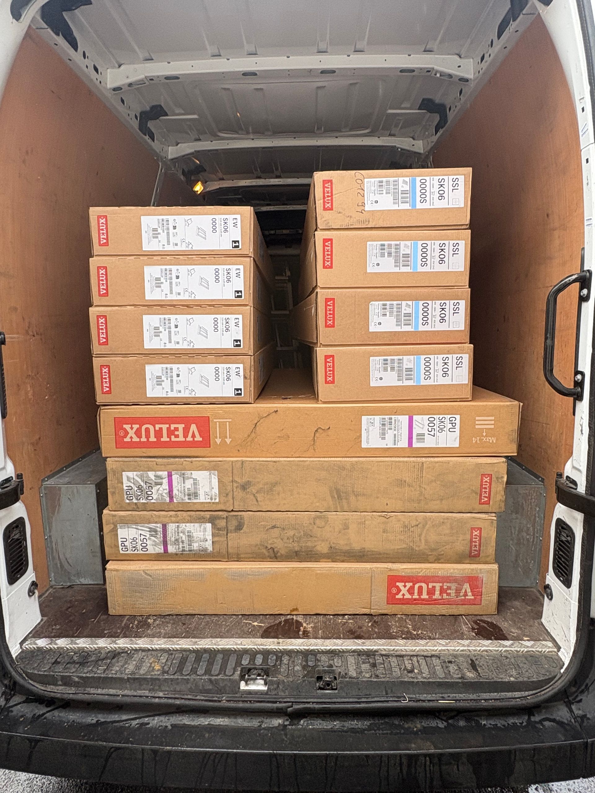 Des cartons de fenêtres de toit Velux et d'autres colis chargés à l'arrière d'une camionnette.