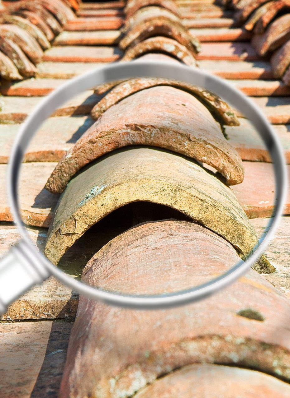 Loupe au-dessus d'un toit de tuiles en terre cuite, mettant en évidence un espace entre les tuiles.