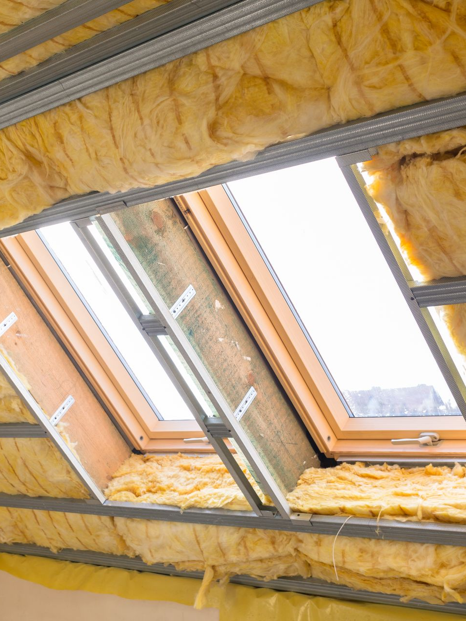 Puits de lumière en construction, entouré d'isolant jaune et d'une structure métallique.