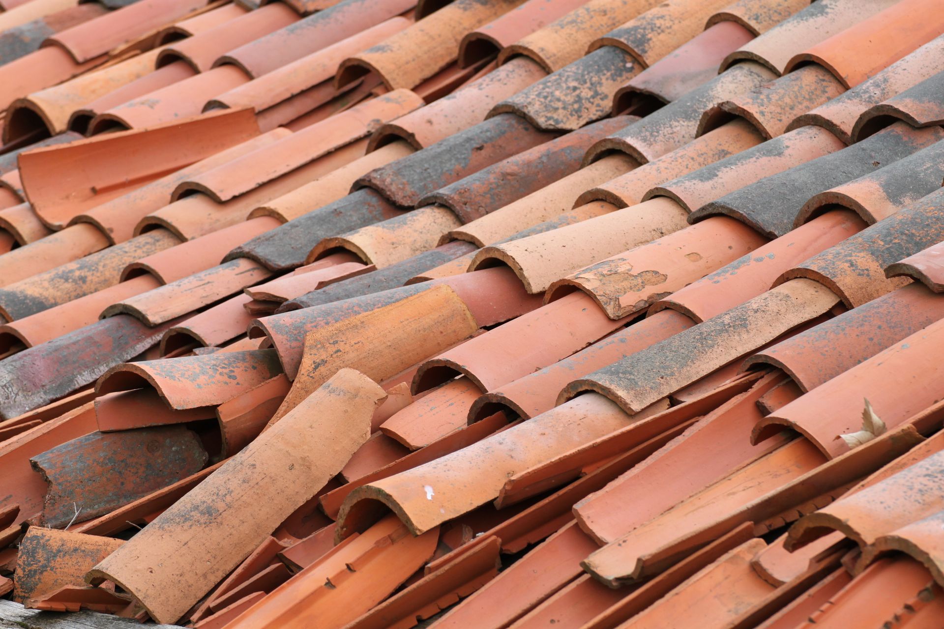 Gros plan sur des tuiles de toit en terre cuite rouge cassées.