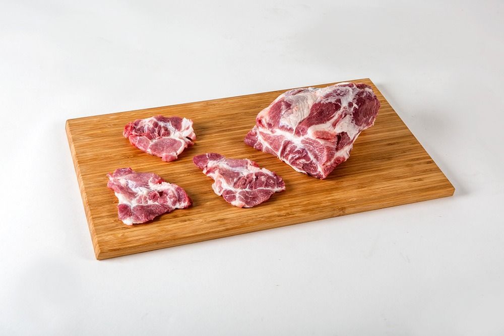 Un trozo de carne está sobre una tabla de cortar de madera.