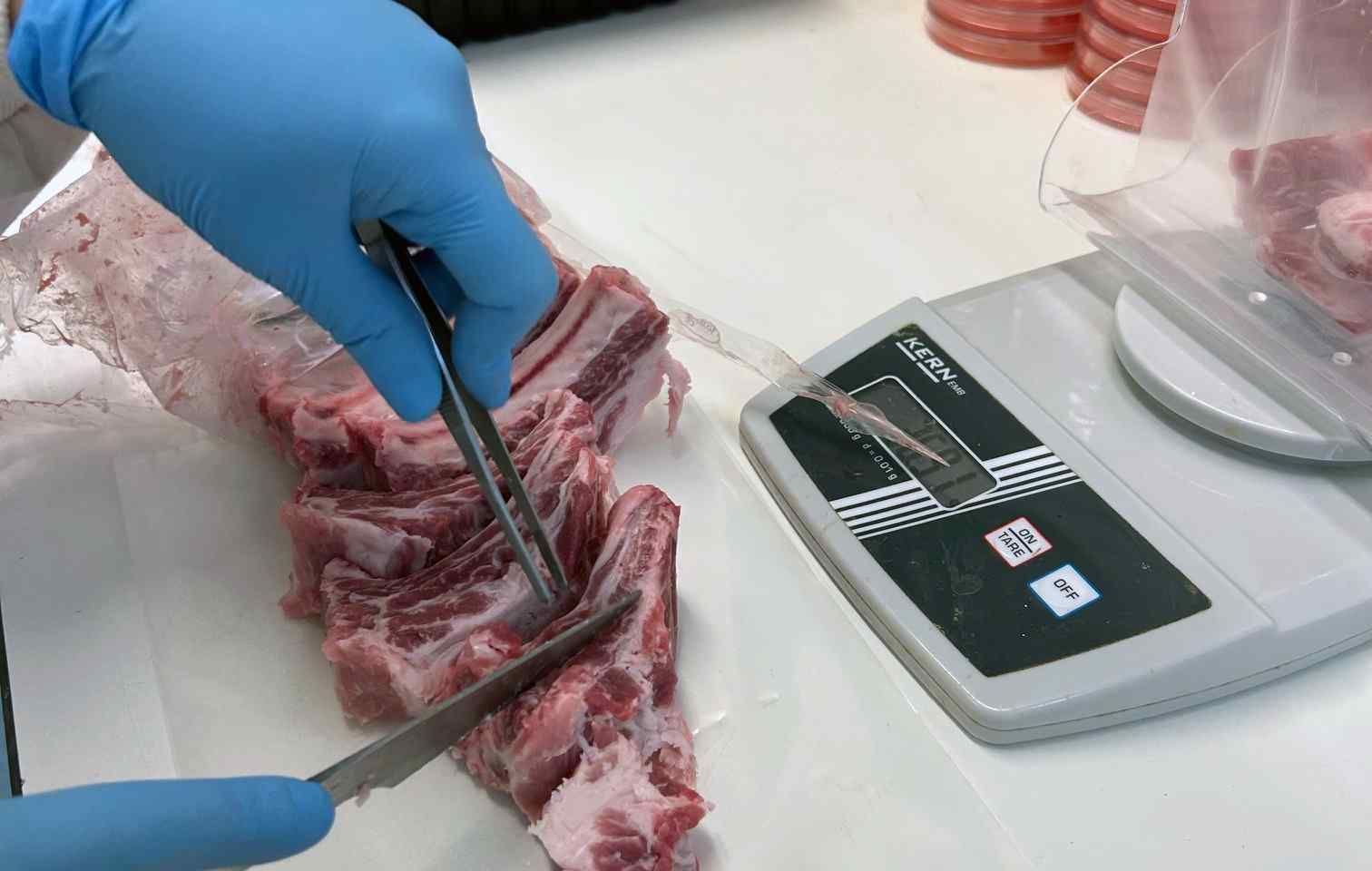 Una persona está cortando un trozo de carne al lado de una báscula.