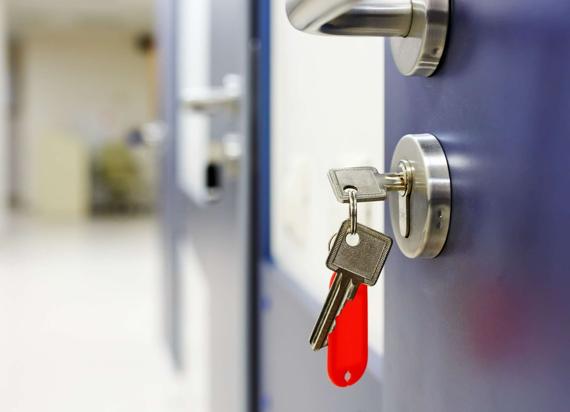 Dos llaves cuelgan de una cerradura en una puerta azul.