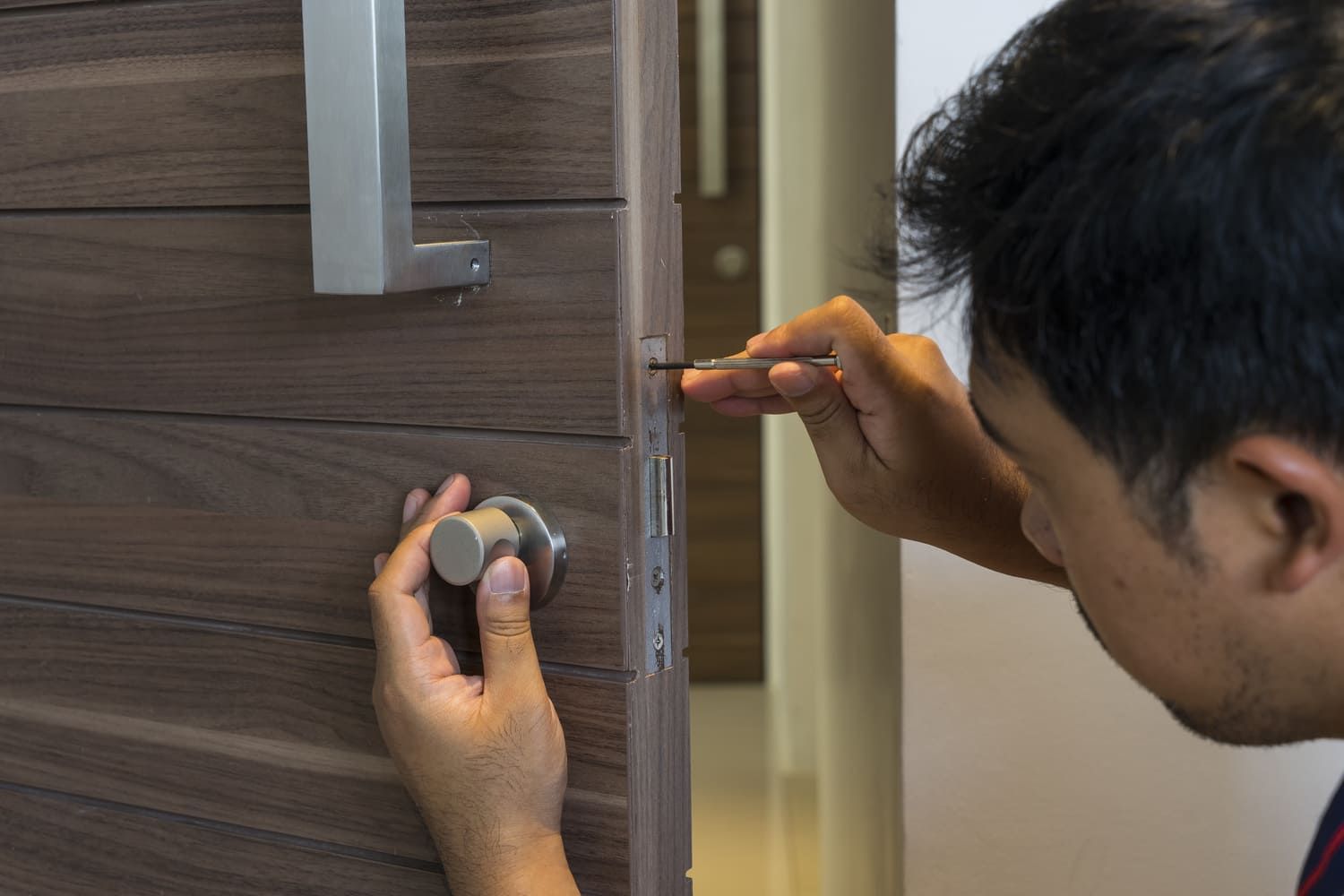 Un hombre está arreglando una puerta con un destornillador.