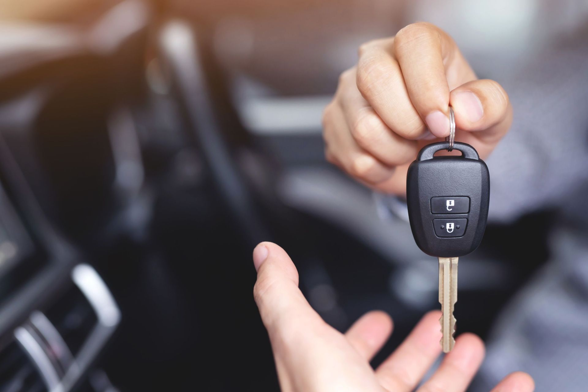 Una persona le entrega una llave de coche a otra persona en un coche.