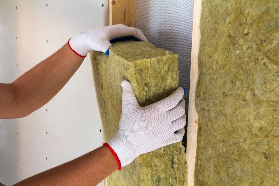 Un hombre está midiendo un trozo de panel de yeso con una cinta métrica.