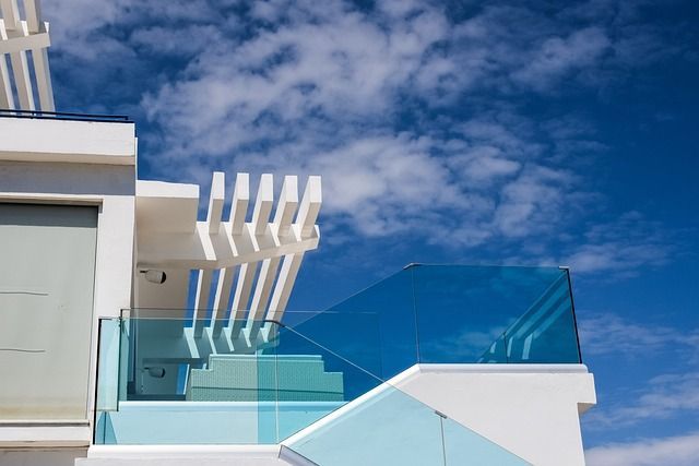 Un edificio blanco con barandilla de cristal y escaleras.