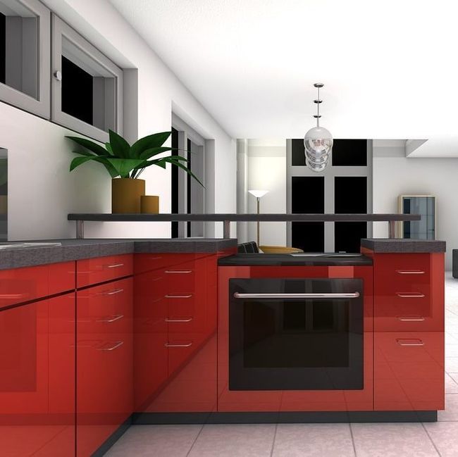 Una cocina con gabinetes rojos y un horno negro.
