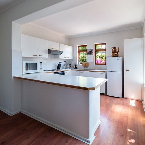Una cocina con gabinetes blancos y un refrigerador blanco.
