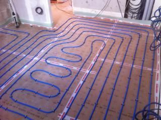 Tuyaux en cuivre et vase d'expansion rouge dans un environnement industriel avec un sol gris et des murs blancs.