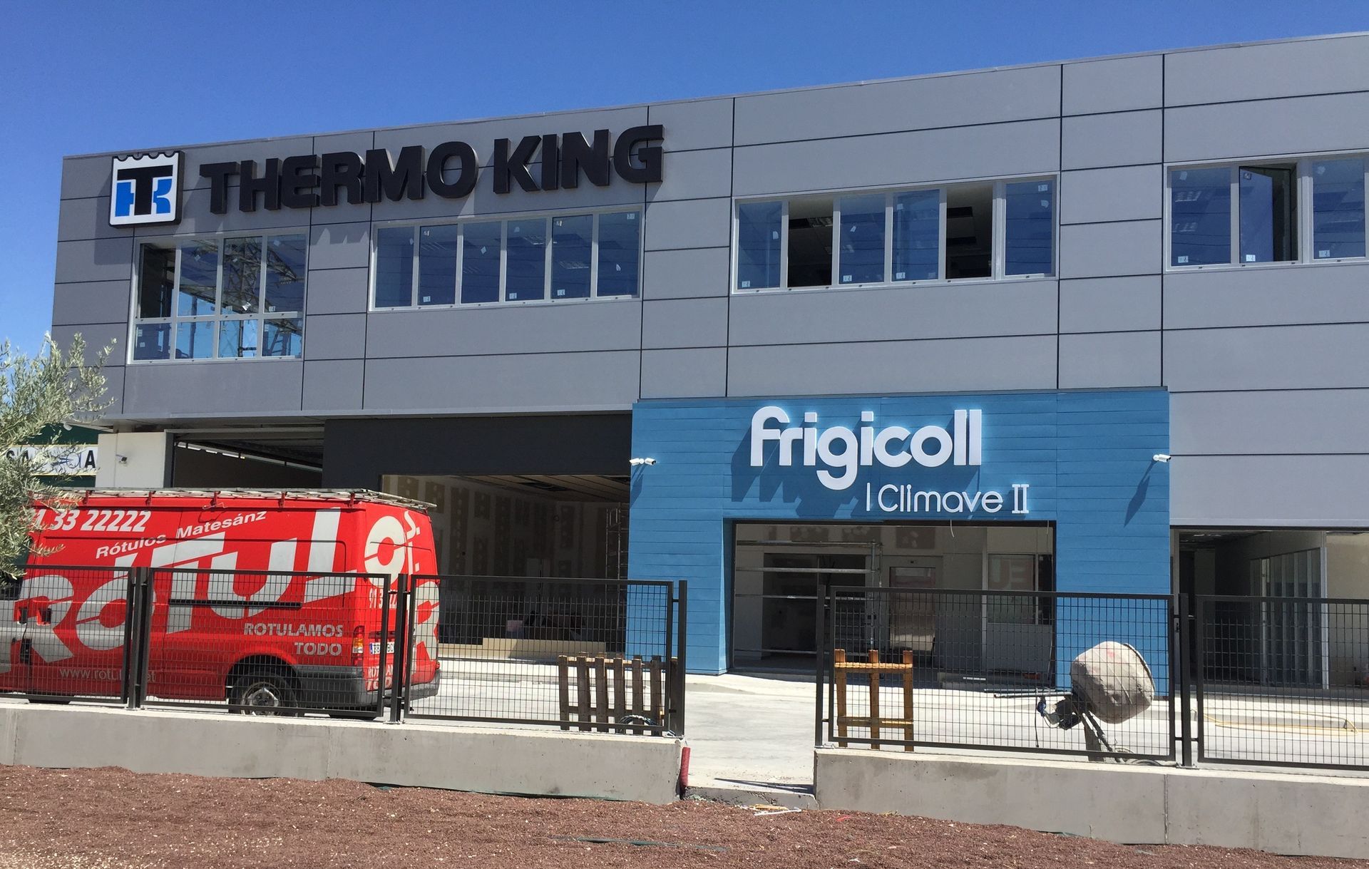 Una camioneta roja está estacionada frente a un edificio que dice frigicoll