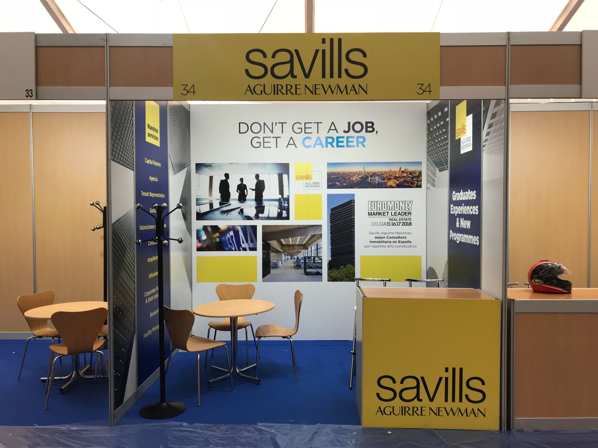 Un stand de Savills con mesas y sillas y un cartel que dice