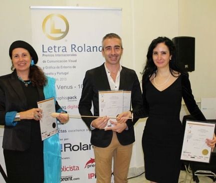 Tres personas paradas frente a un cartel que dice letra roland