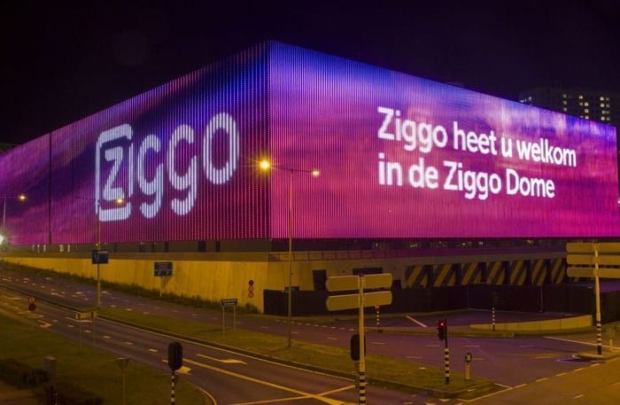 Un gran edificio con la palabra ziggo escrita en él se ilumina por la noche.