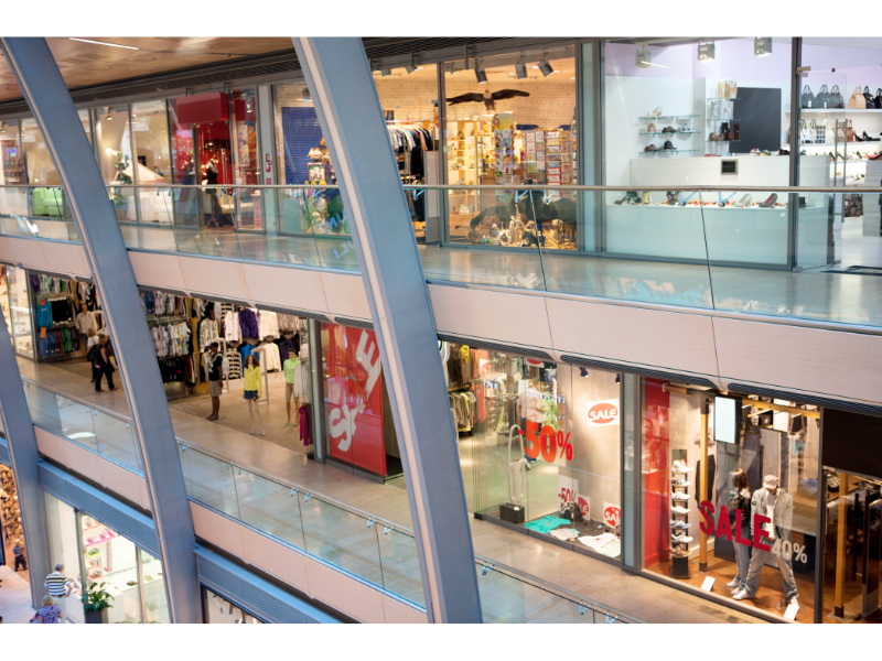 Un centro comercial con muchas tiendas y gente paseando.