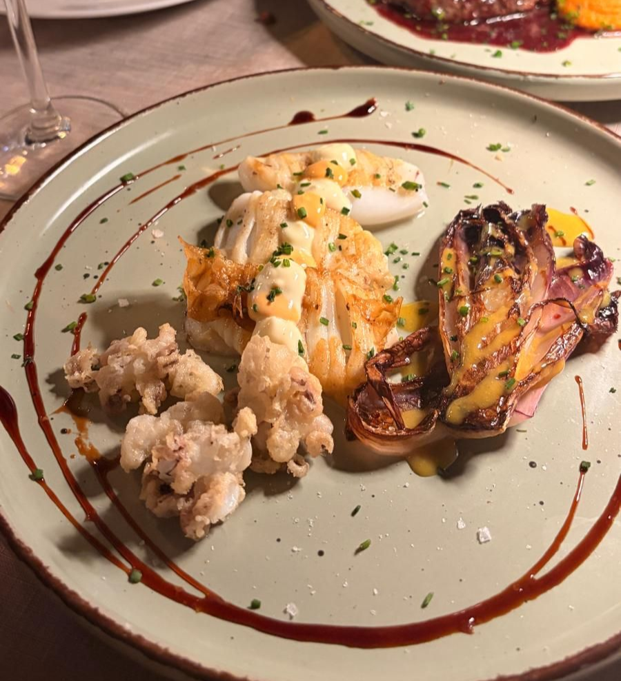 Plato gourmet con huevo escalfado, verduras asadas y salsa rociada sobre un plato blanco