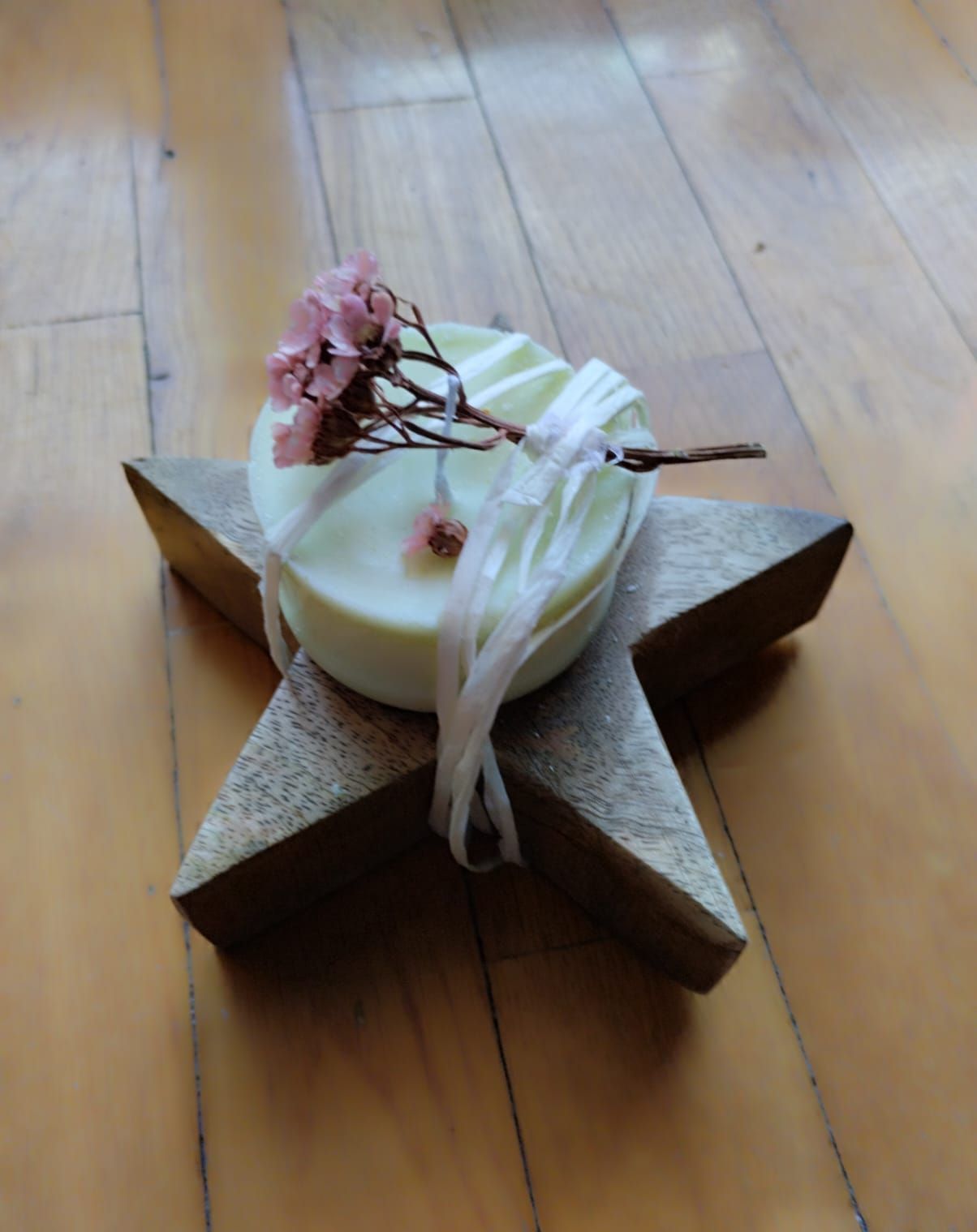 Hay tres velas sobre una mesa al lado de flores.