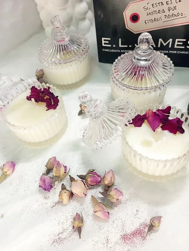 Hay tres velas sobre una mesa al lado de flores.