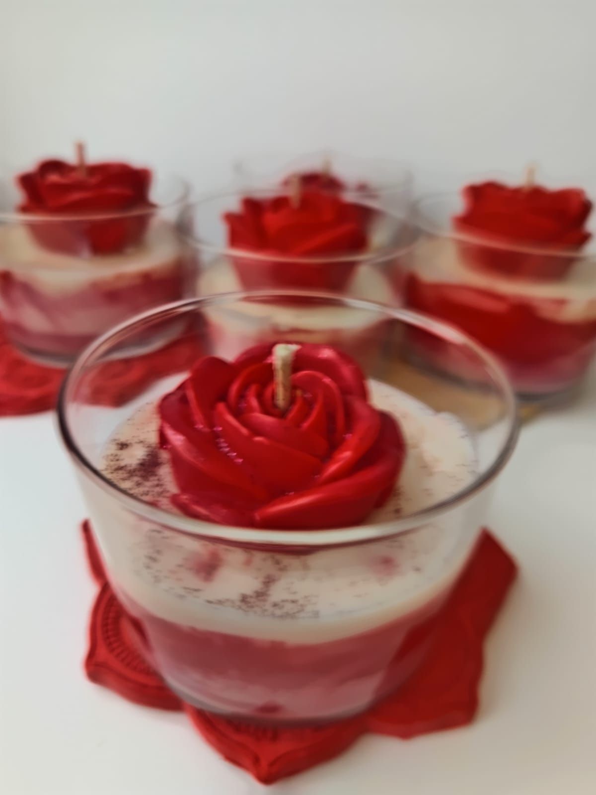 Una vela en un vaso con una rosa roja encima