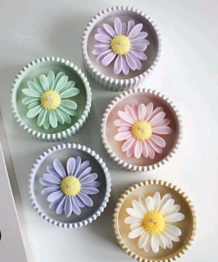 Hay tres velas sobre una mesa al lado de flores.