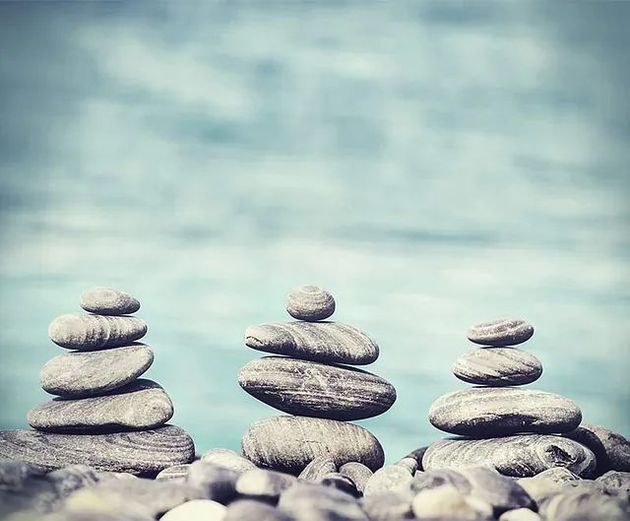 Tres pilas de rocas están apiladas una encima de otra en una playa.