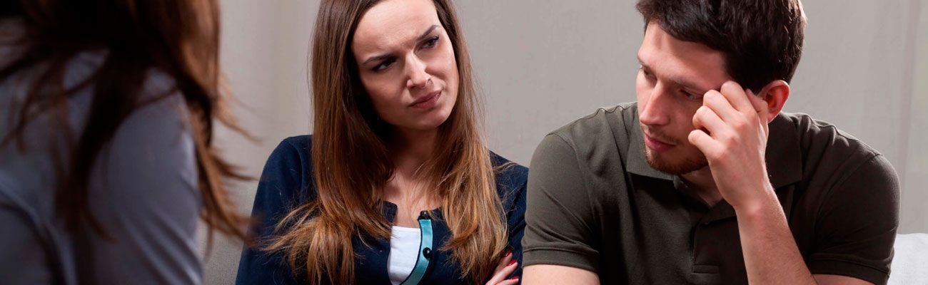 Un hombre y una mujer están sentados en una mesa hablando con una mujer.