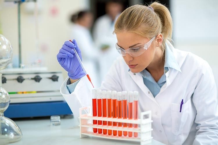 Un científico pipetea líquido en tubos de ensayo en un laboratorio.