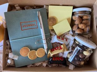 Una caja llena de un diario, un bolígrafo, bastones de caramelo y nueces.