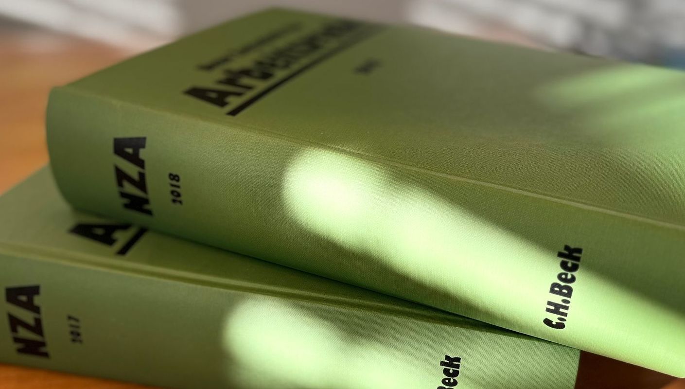 Eine Person hält ein Tablet neben einem Stapel Bücher und einer Waage der Gerechtigkeit.