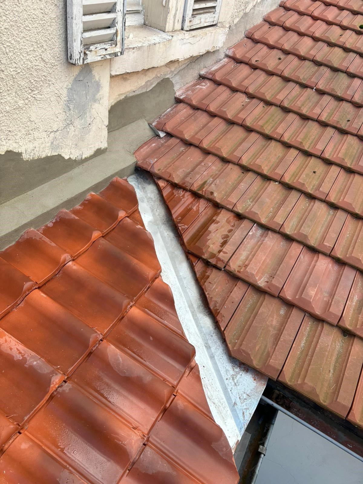 Tuiles rouges séparées par un élément de zinguerie.
