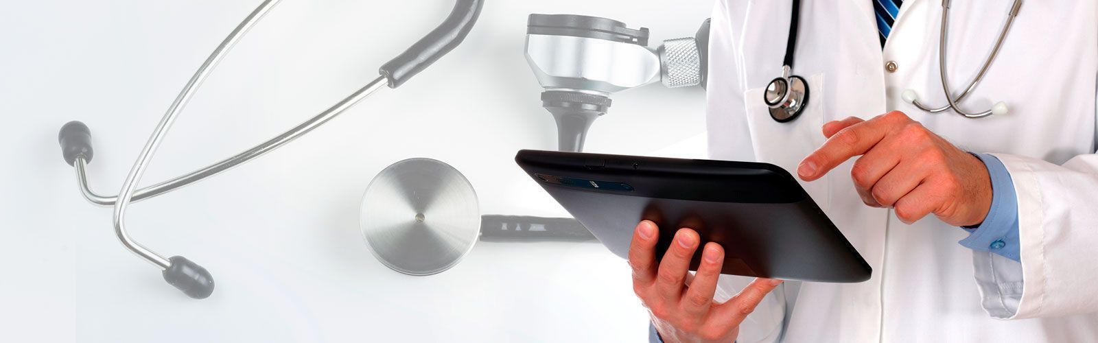 Un profesional sanitario con bata blanca de laboratorio utilizando una tableta, con un estetoscopio colgado al cuello.