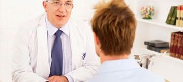 Un médico con bata blanca y corbata atiende a un paciente en un consultorio luminoso y profesional.