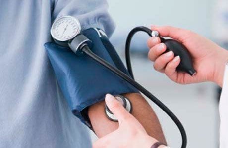 Un profesional médico utiliza un estetoscopio y un tensiómetro manual para examinar el brazo de un paciente.