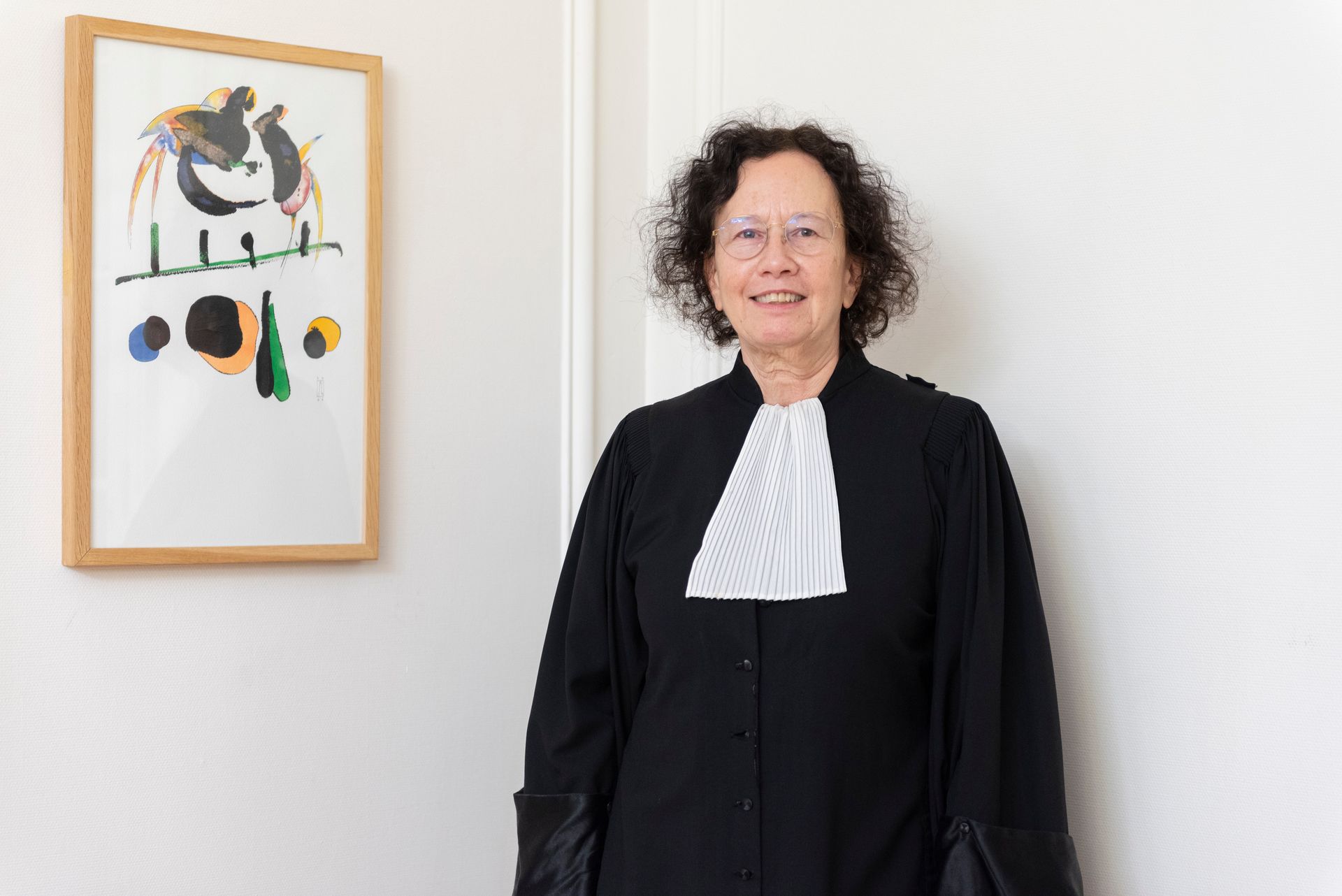 Femme debout à côté d'une œuvre d'art abstraite encadrée sur un mur blanc.