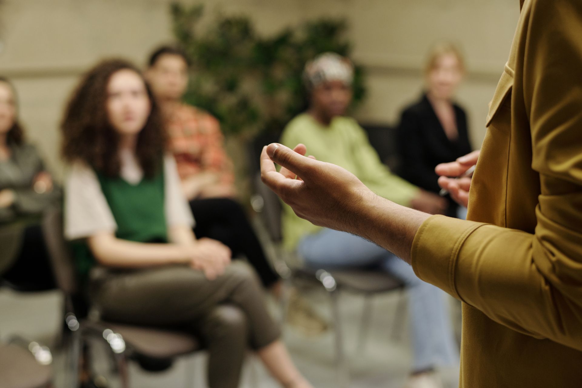 Un orateur lors d'un séminaire, tandis qu'un public assis écoute en arrière-plan.