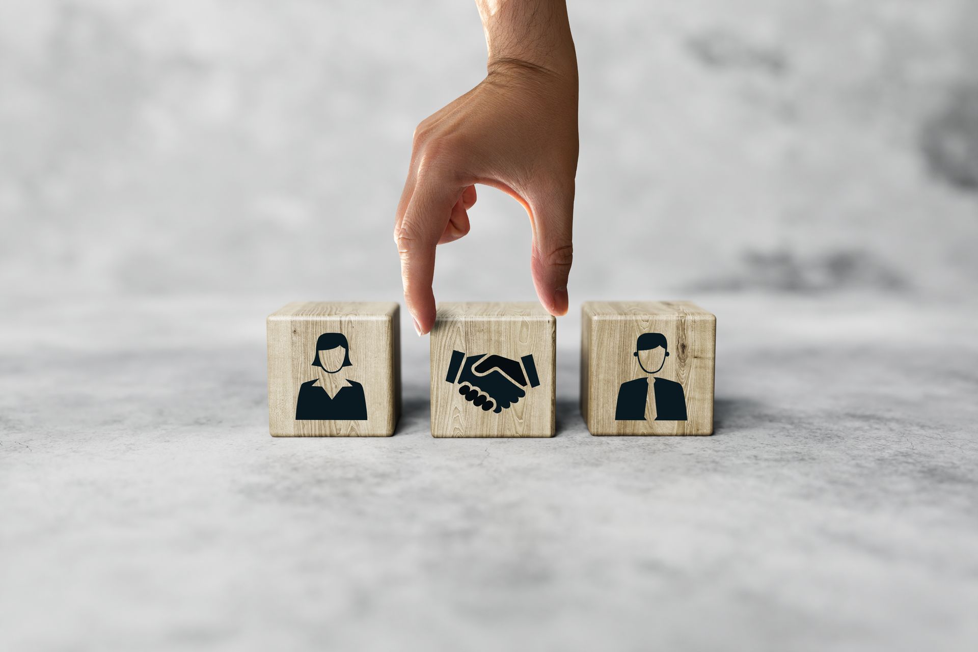 Choisir manuellement le bloc central orné d'une icône de poignée de main parmi trois blocs de bois disposés sur une table