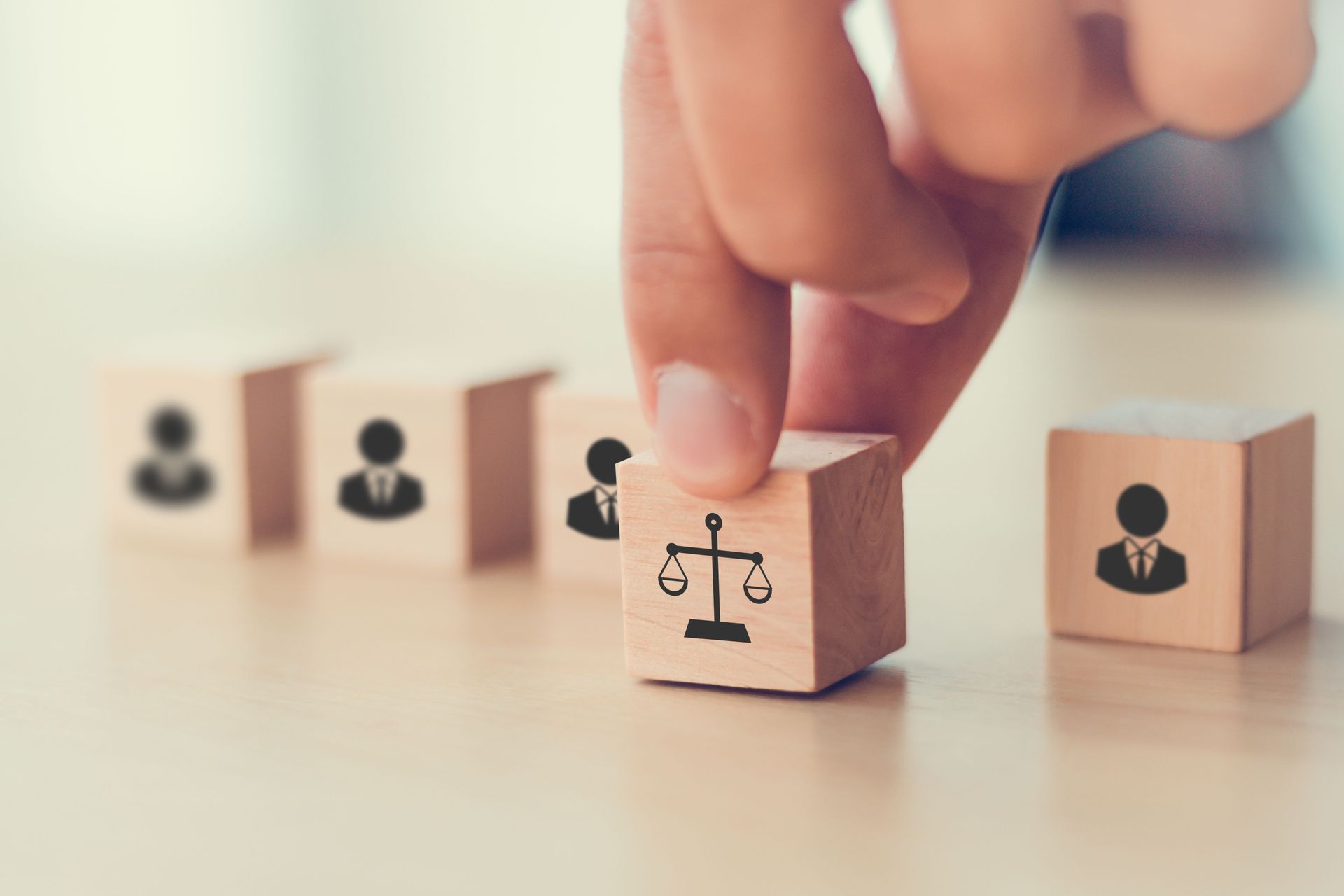 Une main déposant un bloc représentant le symbole de la justice parmi d'autres blocs d'icônes commerciales sur une table