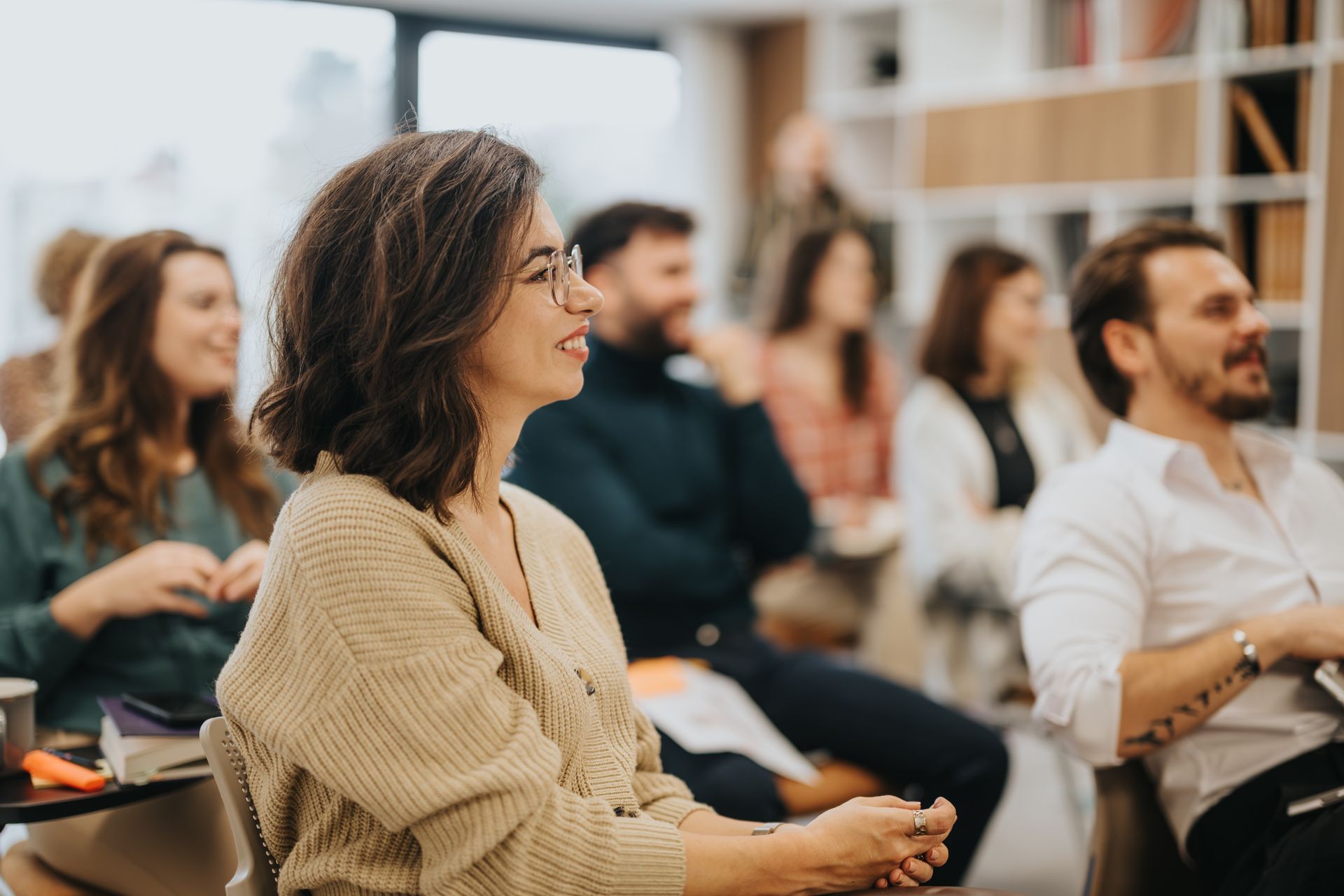 Des personnes assises dans une salle de classe ou un atelier lumineux, écoutant attentivement.