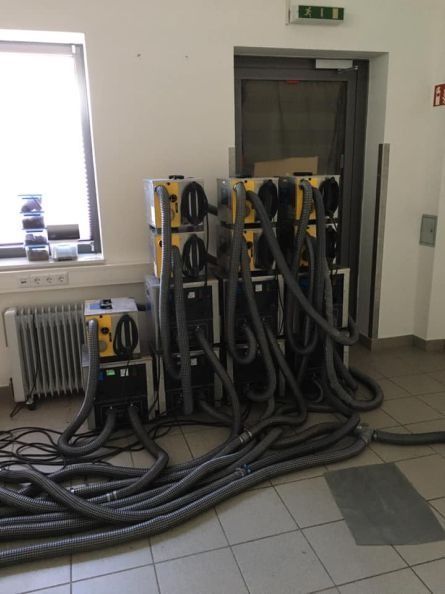Industrieraum mit aufgerollten schwarzen Schläuchen und Gerätegestellen in der Nähe einer Tür und eines Fensters.