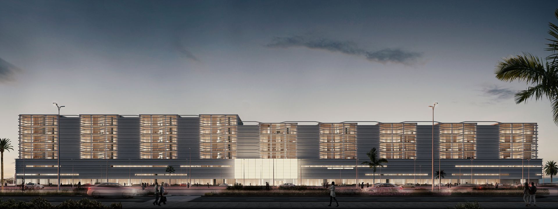 Un edificio moderno con ventanas iluminadas al atardecer. Palmeras y farolas bordean la fachada.