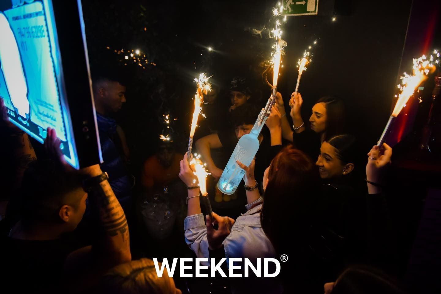 Un grupo de personas sostiene bengalas en una habitación oscura.