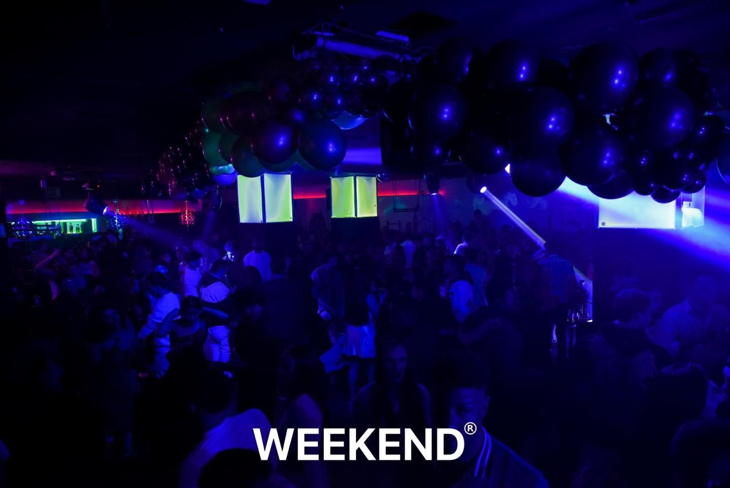 Un grupo de personas está bailando en una habitación oscura con las palabras fin de semana en la parte inferior.