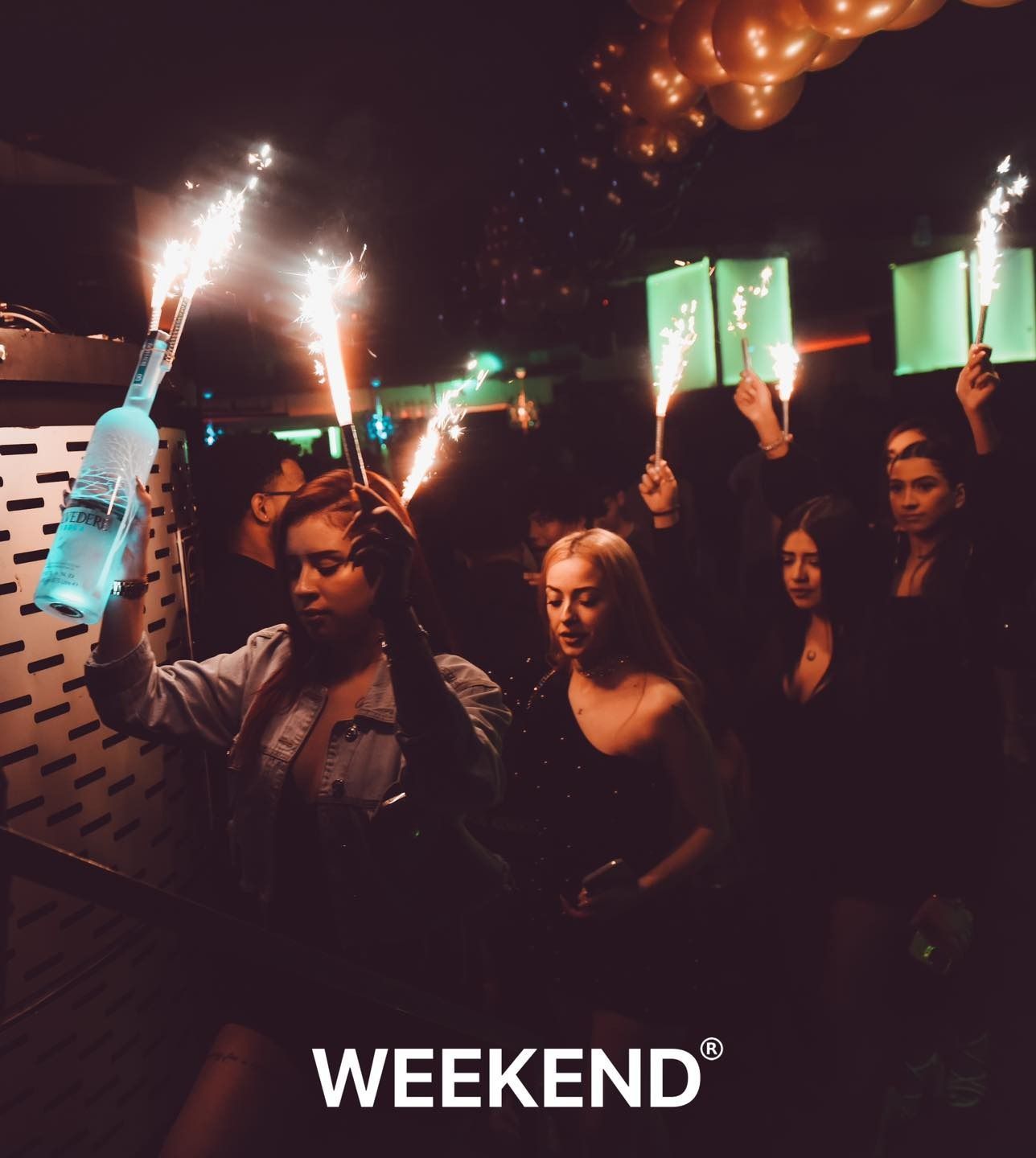 Un grupo de personas sostiene bengalas y una botella de vodka.