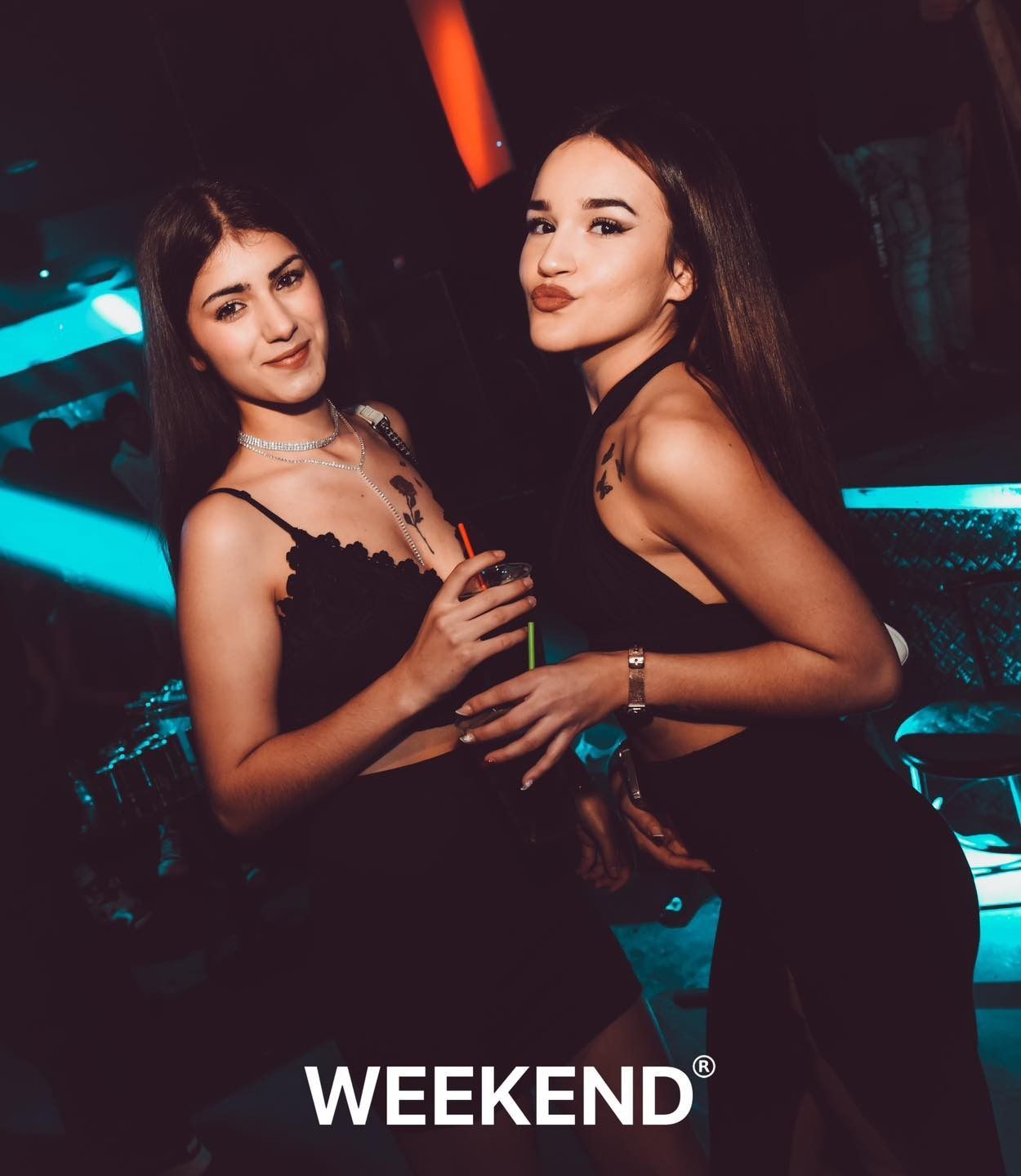Dos mujeres paradas una al lado de la otra en una habitación oscura con la palabra fin de semana escrita en la parte inferior.