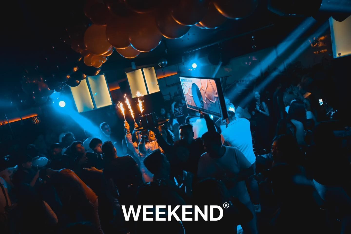 Una multitud de personas está bailando en un club con las palabras fin de semana escritas en la parte inferior.