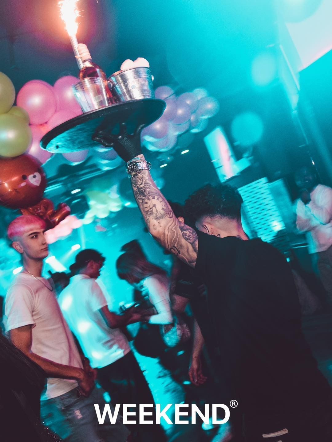 Un hombre sostiene una bandeja con una vela encima en un club.