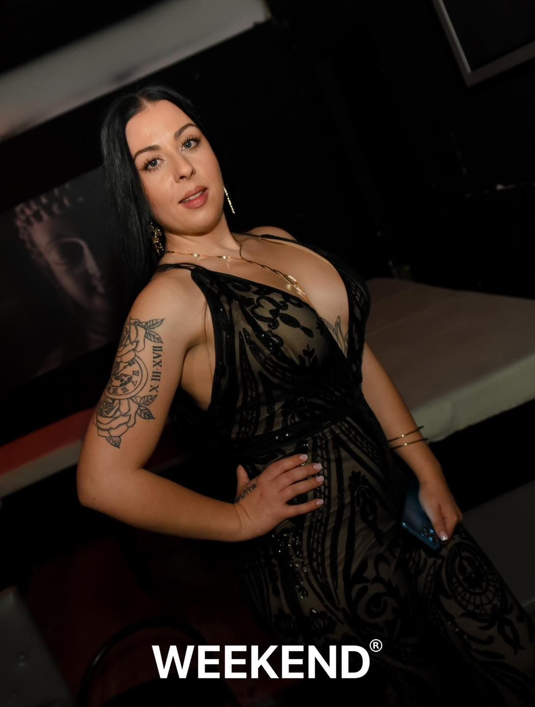 Una mujer con un vestido negro está parada en una habitación oscura.