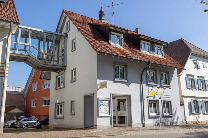 Ein Mann und eine Frau sitzen auf einer Couch, lesen ein Buch und trinken Kaffee.