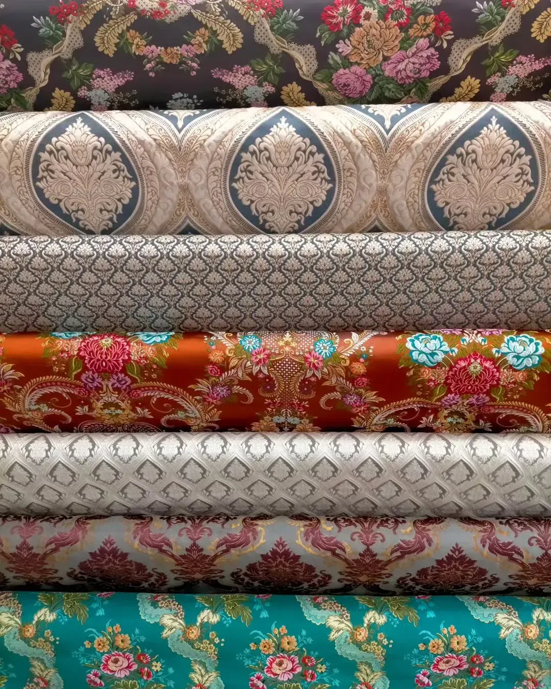 Rollos apilados de tela estampada en varios colores y diseños.