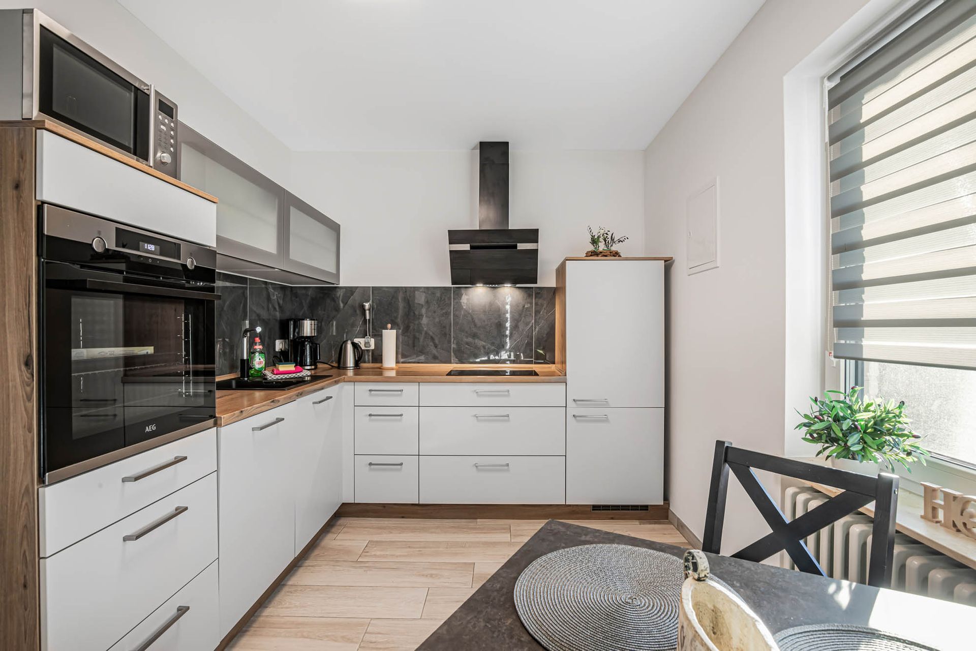 Eine Küche mit weißen Schränken, Geräten aus Edelstahl, einem Kühlschrank und einer Mikrowelle.